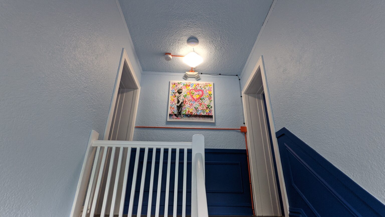 Shared stairwell with blue walls, white railing and colorful artwork