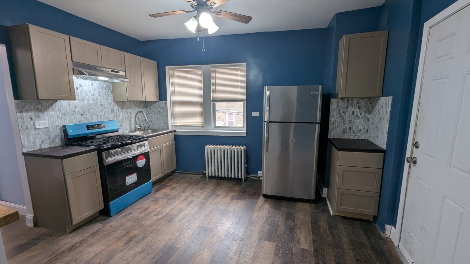 Kitchen with blue walls, stainless steel appliances and wood-look flooring